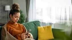 Vrouw zit in de zetel en zoekt een AI psycholoog op met haar telefoon