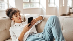 Jonge vrouw scrollend op haar smartphone in de zetel