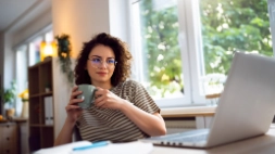 Jonge vrouw met koffietas en laptop