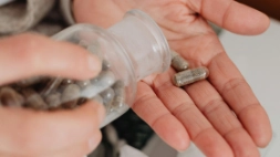 persoon die voedingssupplementen uit een potje neemt