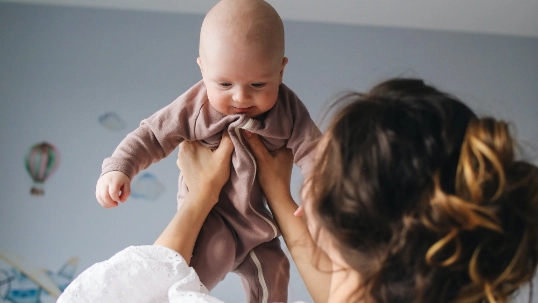 jonge mama met pasgeboren baby in slaapkamer