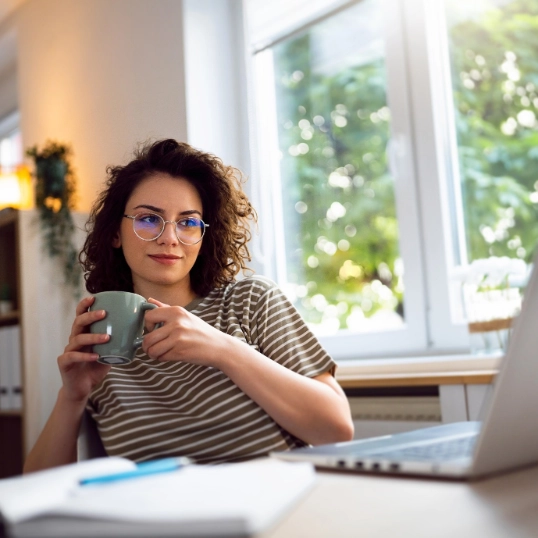 Jonge vrouw met koffietas en laptop