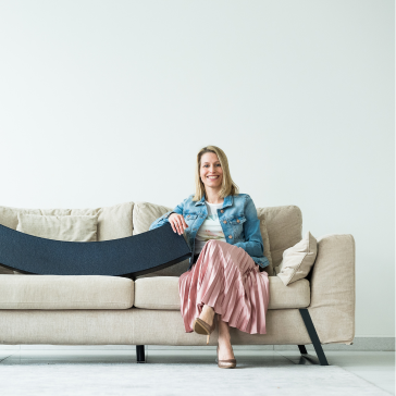 femme assise sur un canapé tenant l'orbi, symbole d'Helan