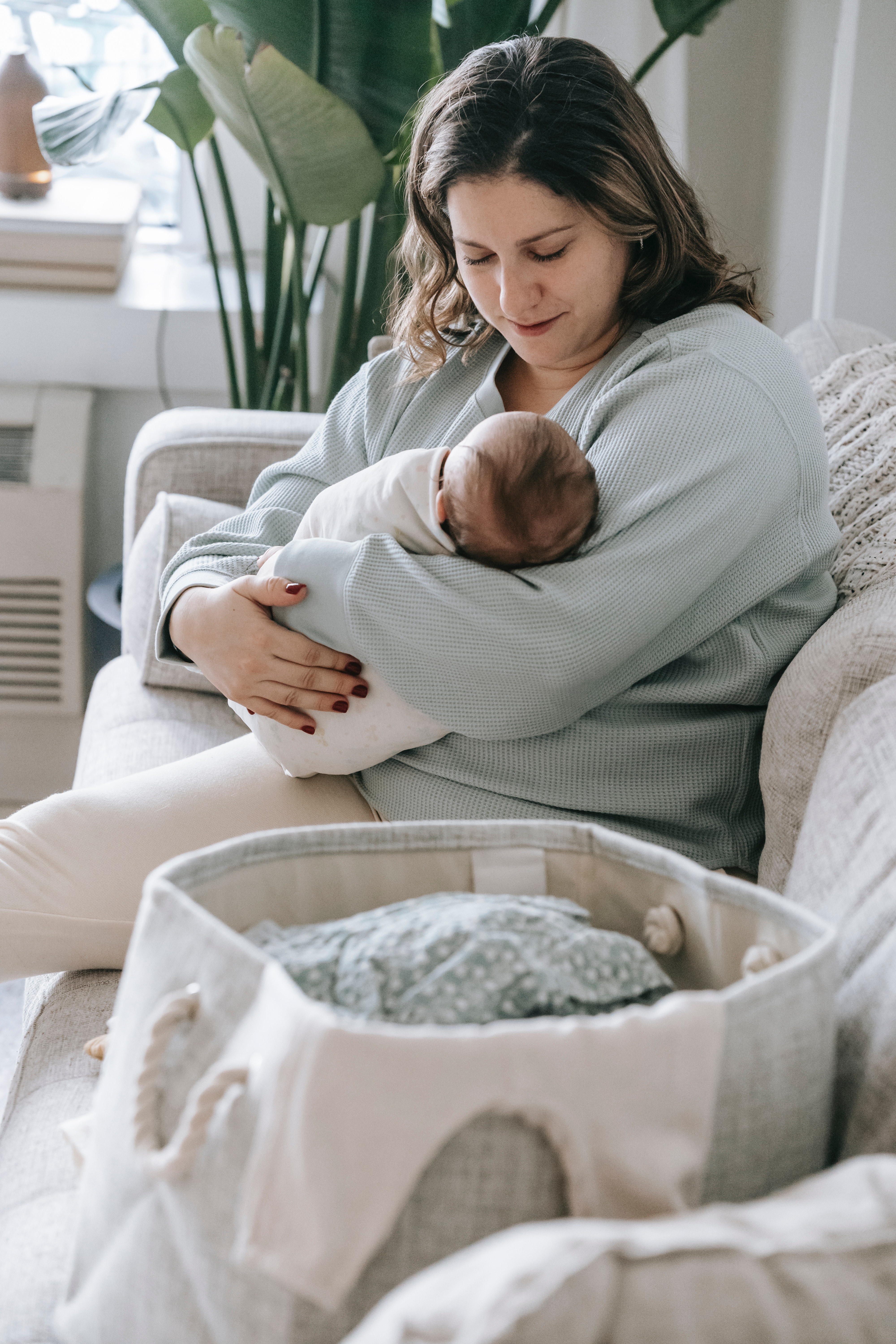 mama zit met ingebakerde baby in de zetel