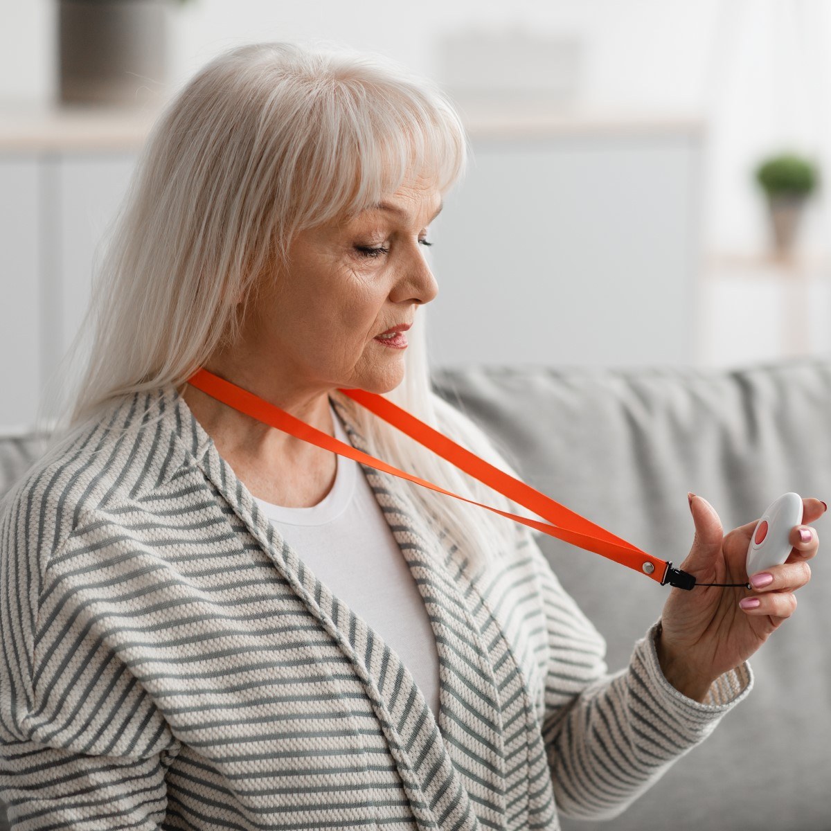 oudere vrouw kijkt naar het personenalarm om haar nek