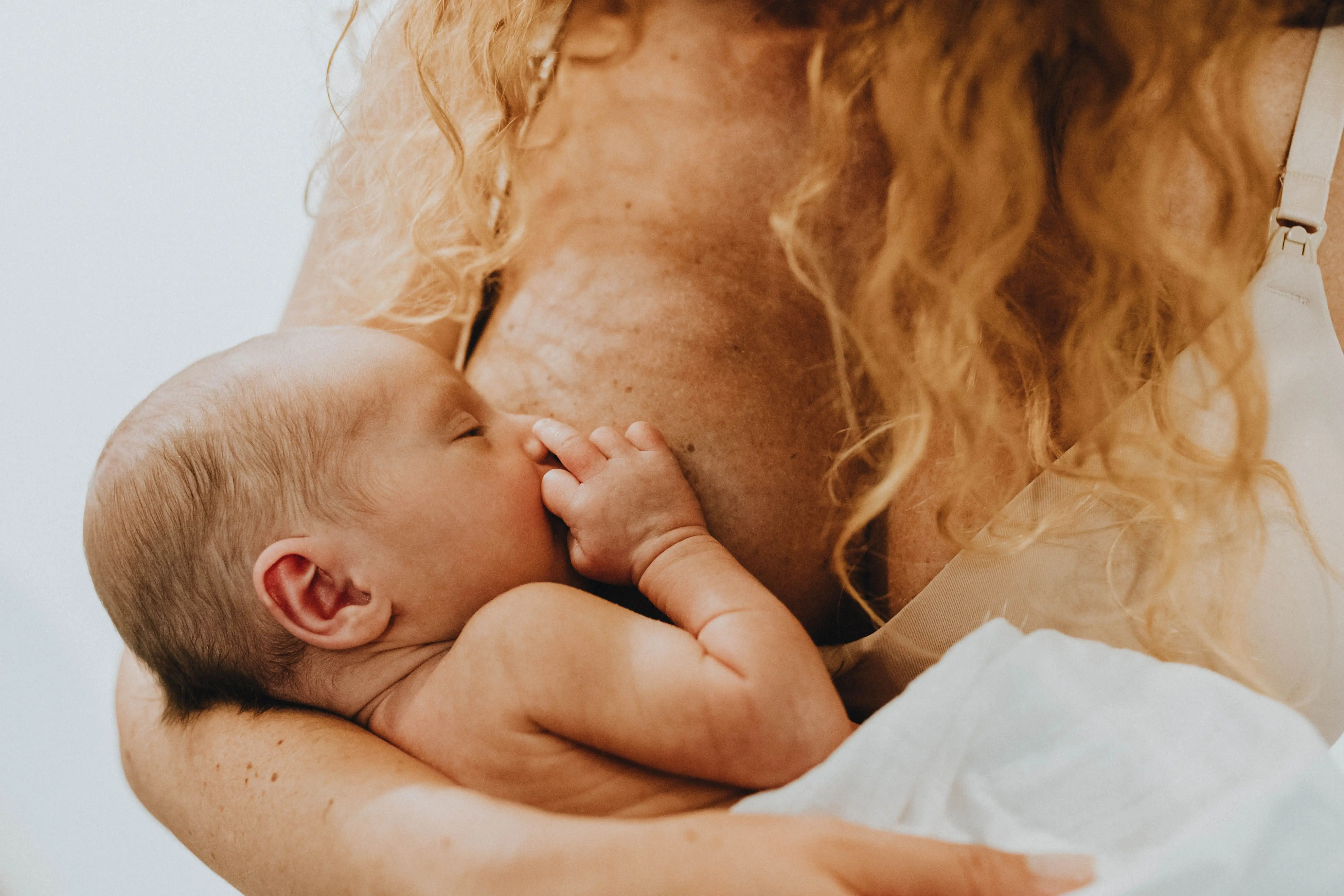 baby drinkt borstvoeding bij mama met rood haar