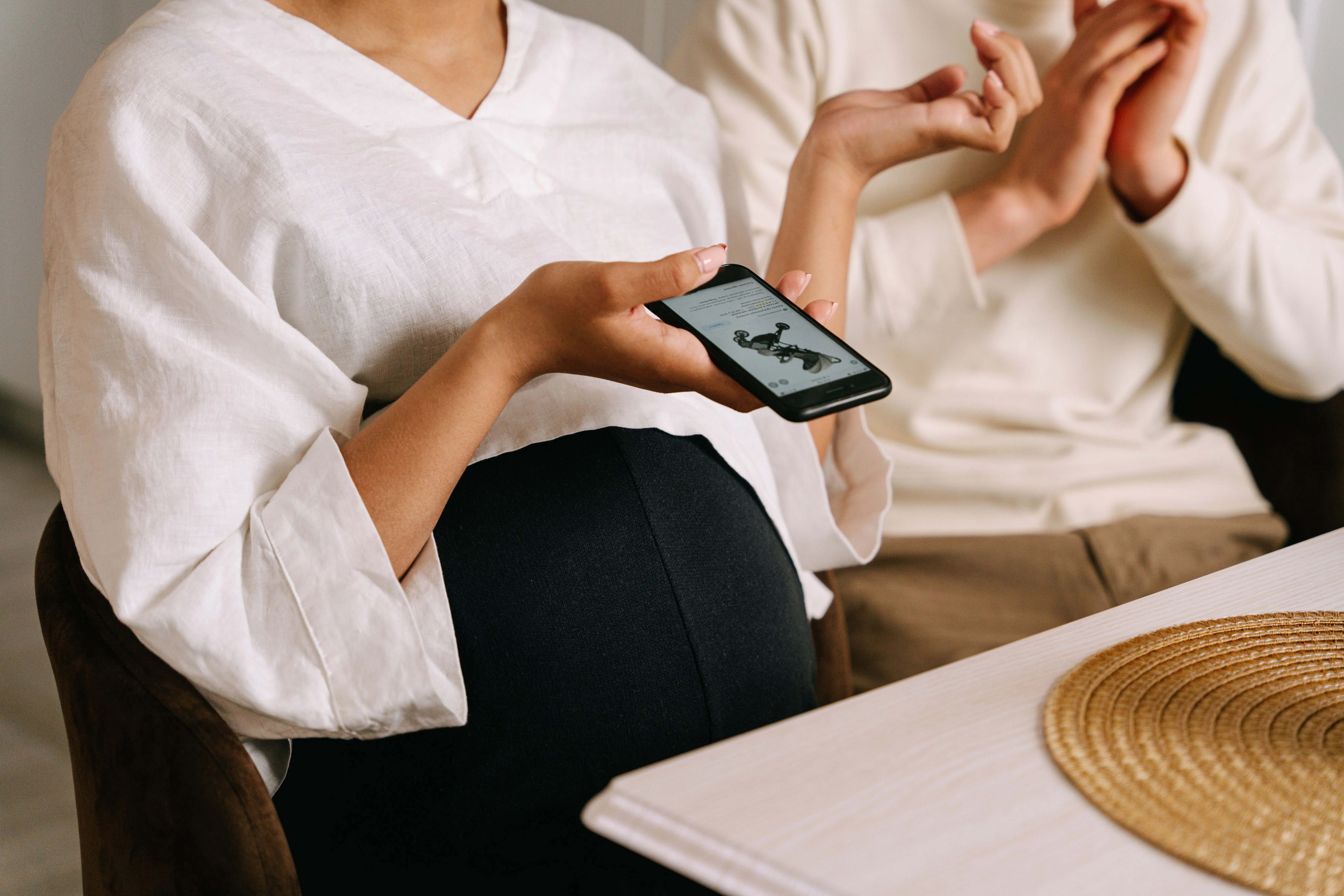 zwangere mama houdt smartphone in de hand met Helan Baby open