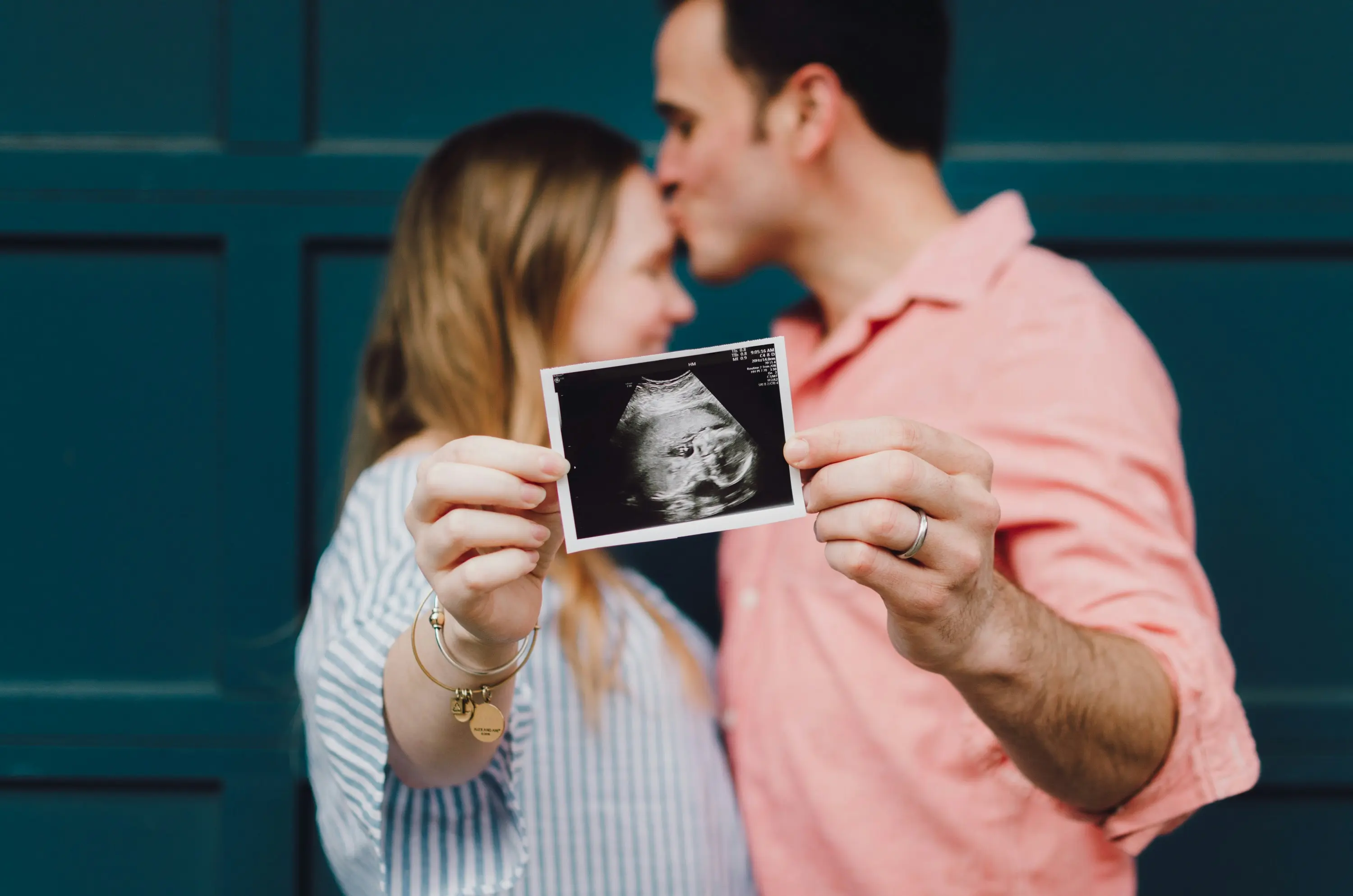 Man kust vrouw op voorhoofd, samen houden ze echo baby vast