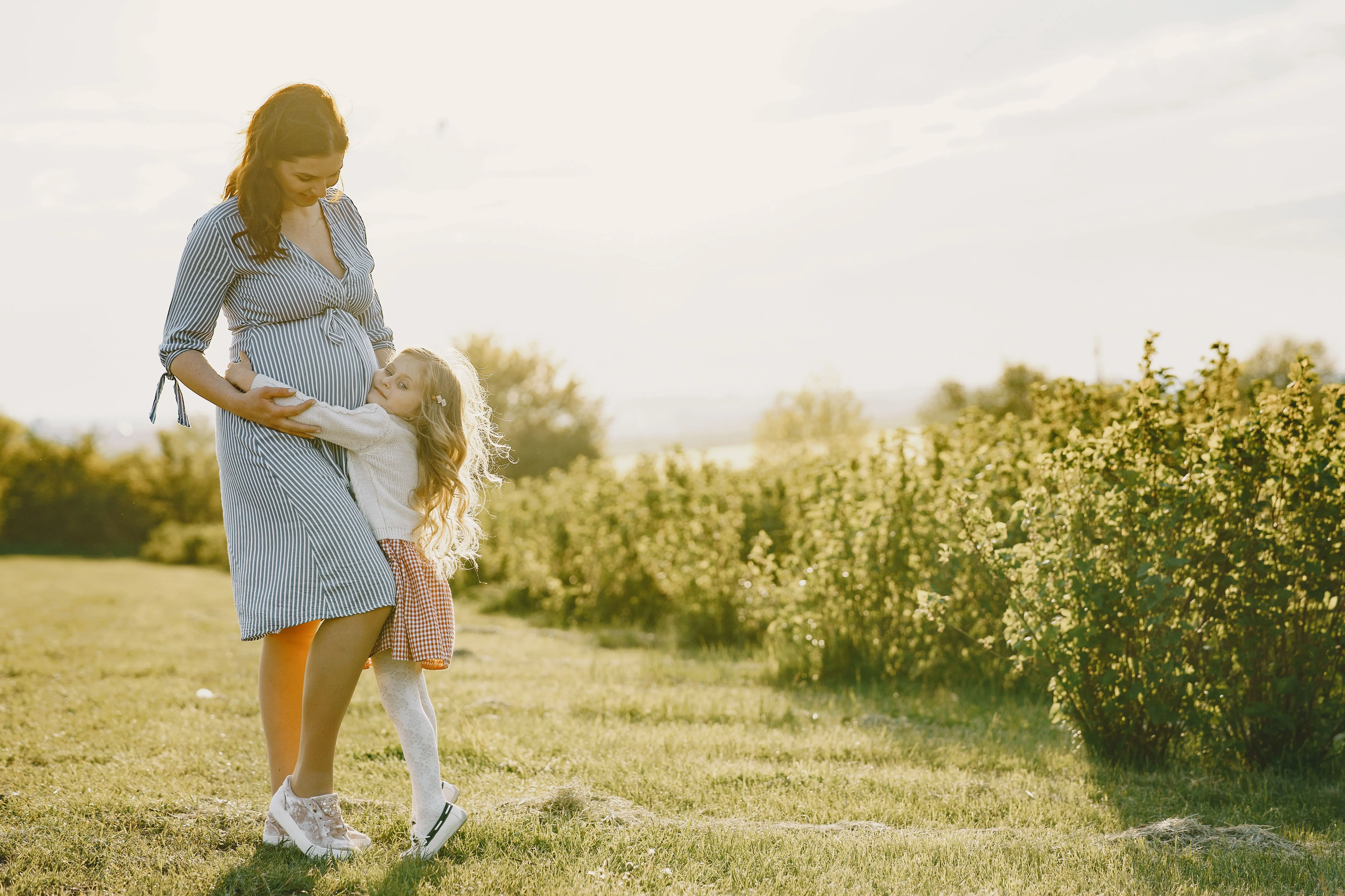 kindje knuffelt met haar zwangere mama