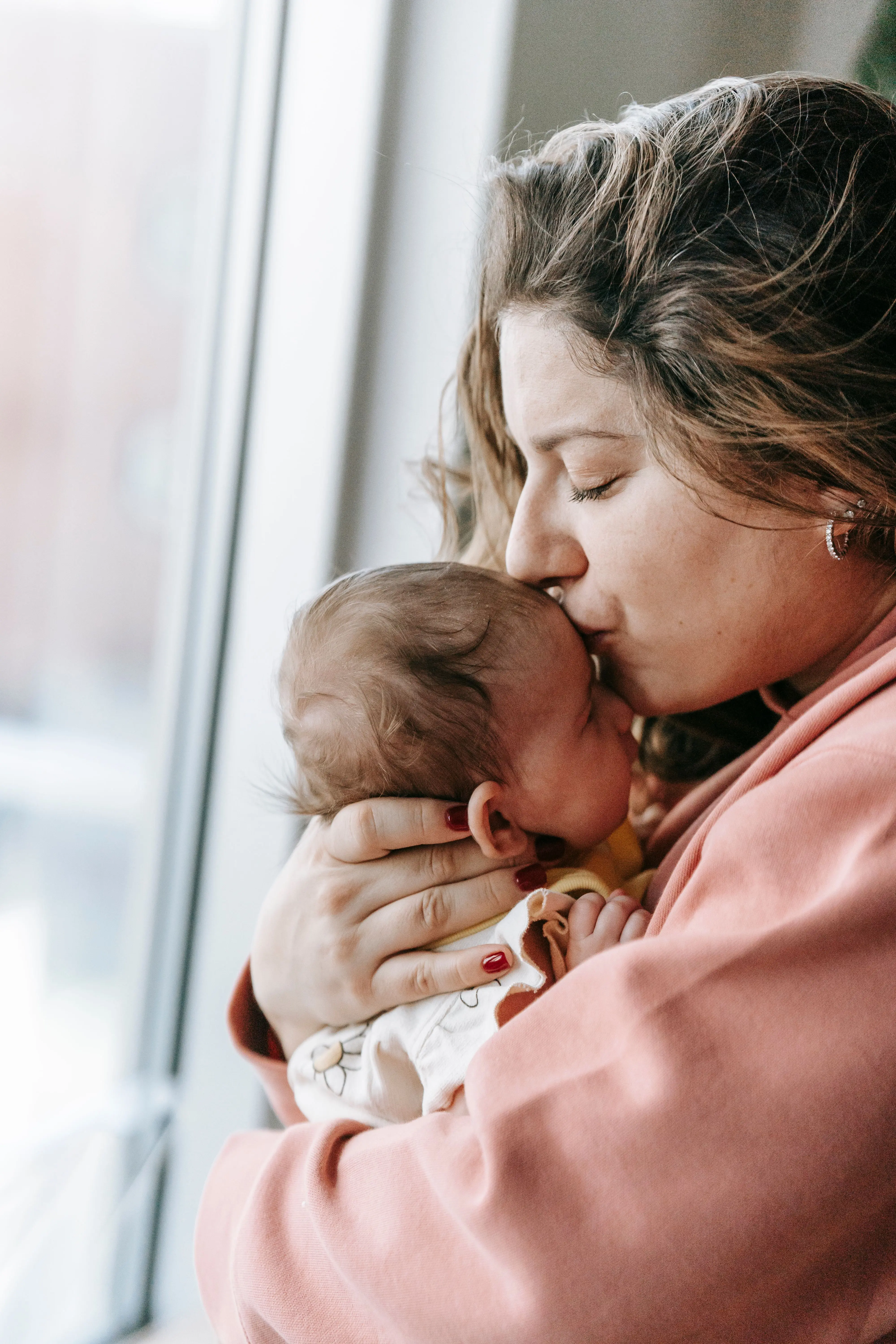 mama kust baby op het voorhoofd
